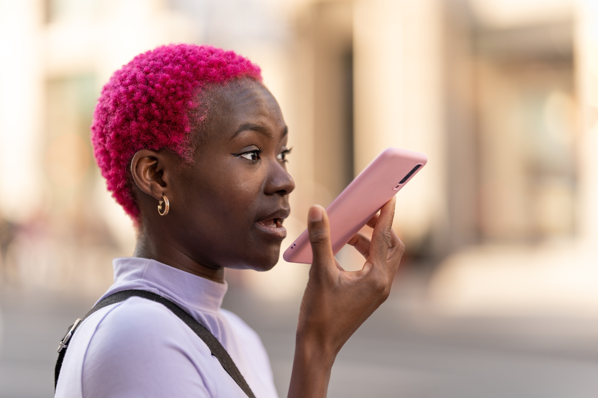 African young woman sending a voice message with the mobile outdoors