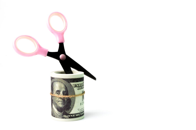 Money banknotes and scissors over white background