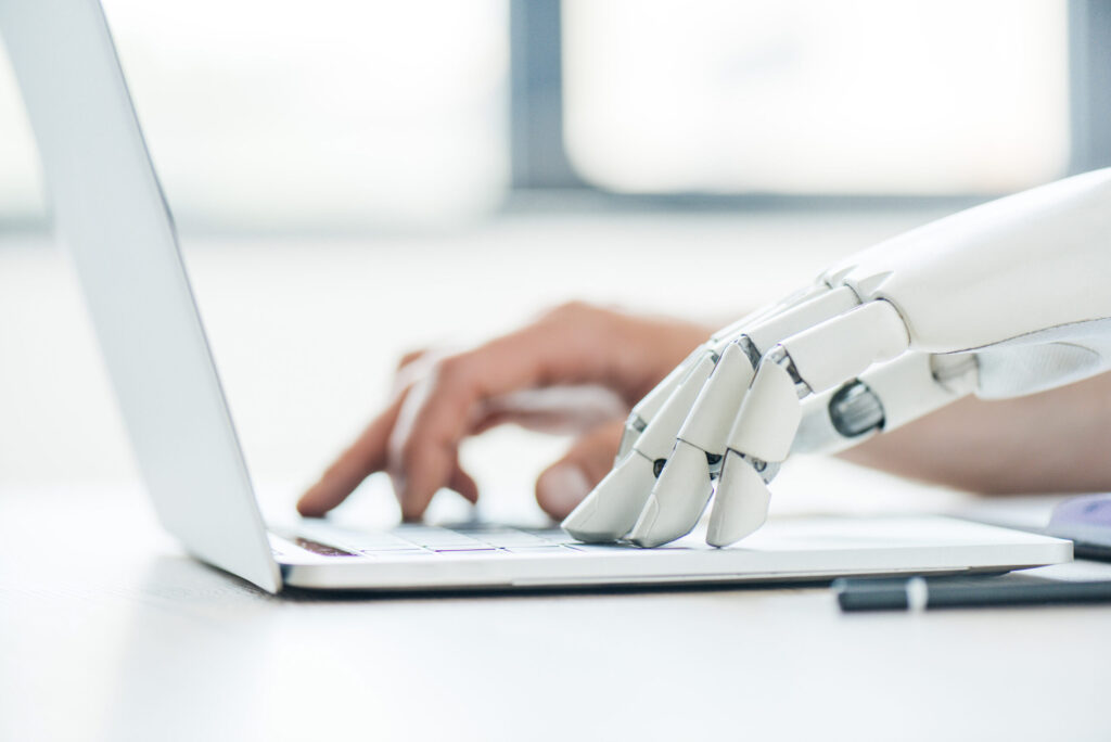 Robotic hand on laptop making AI-generated content